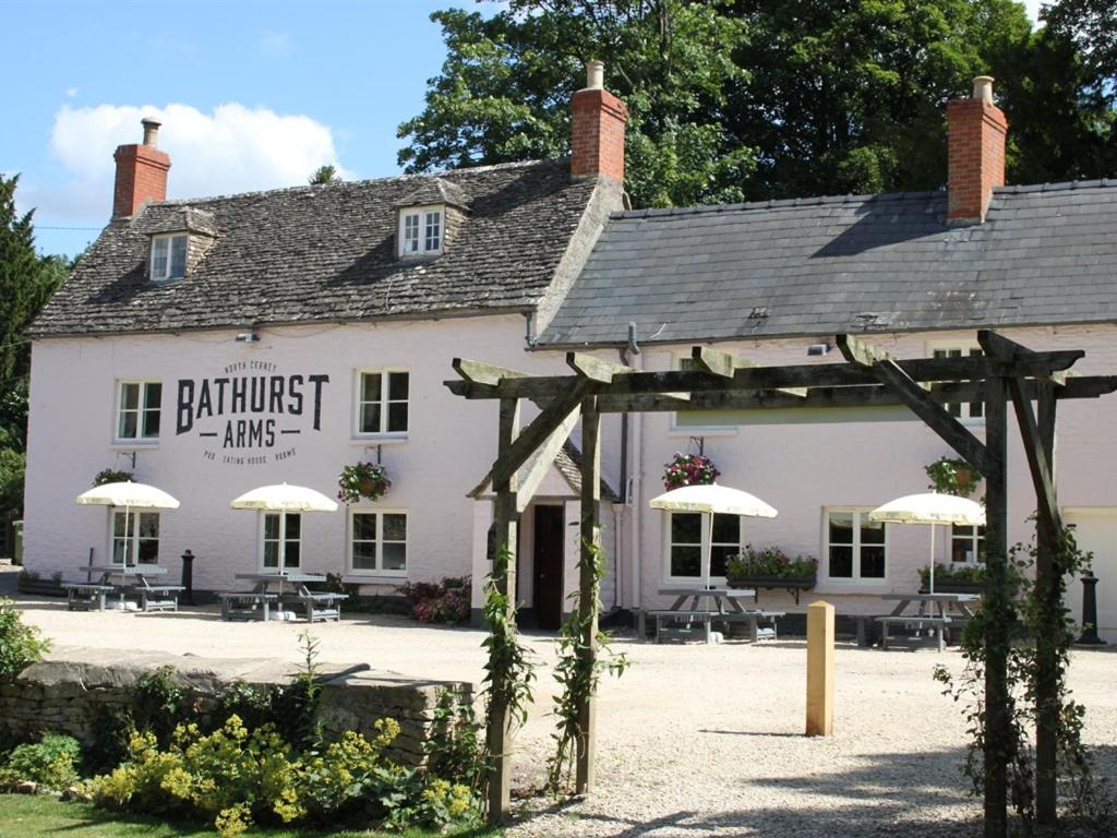 Biały budynek z parasolami przed nim w obiekcie The Bathurst Arms w mieście Cirencester