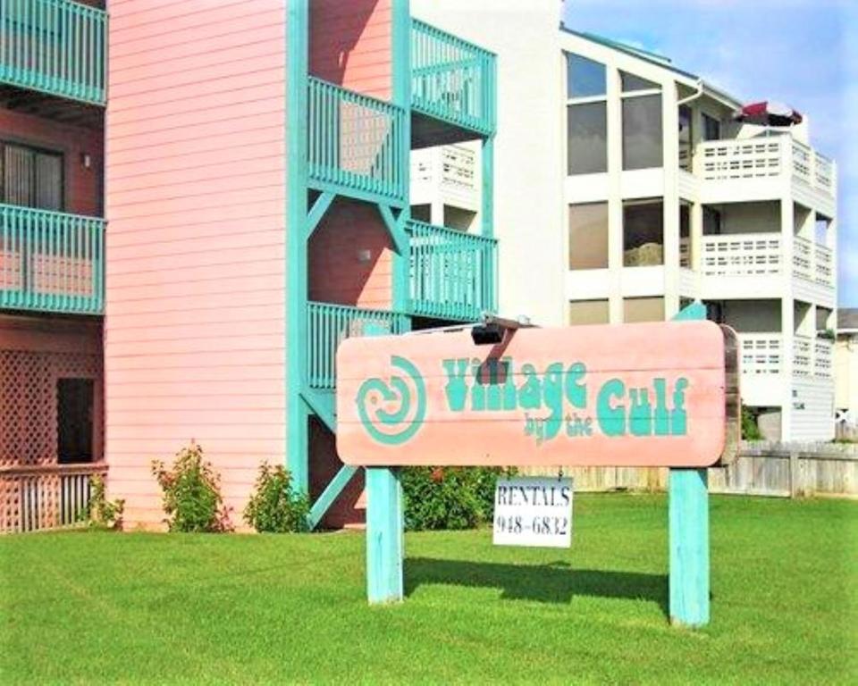 un panneau dans l'herbe devant un bâtiment dans l'établissement Village by the Gulf, à Gulf Shores
