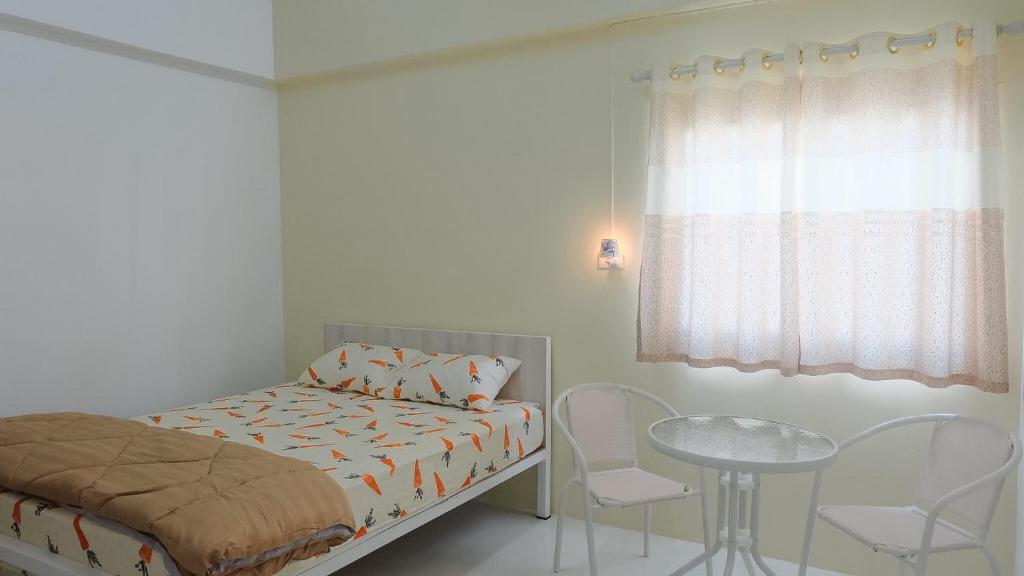 um quarto com uma cama, uma mesa e cadeiras em Baankanjana em Hat Yai