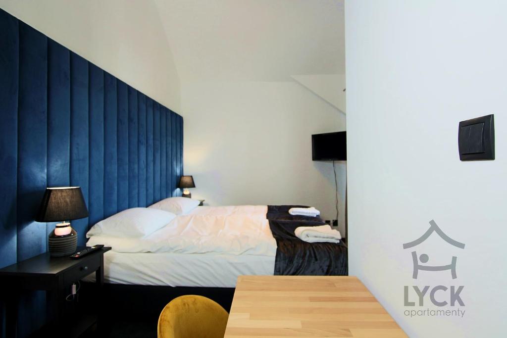 a bedroom with a bed and a desk and a table at Lyck Apartamenty in Ełk