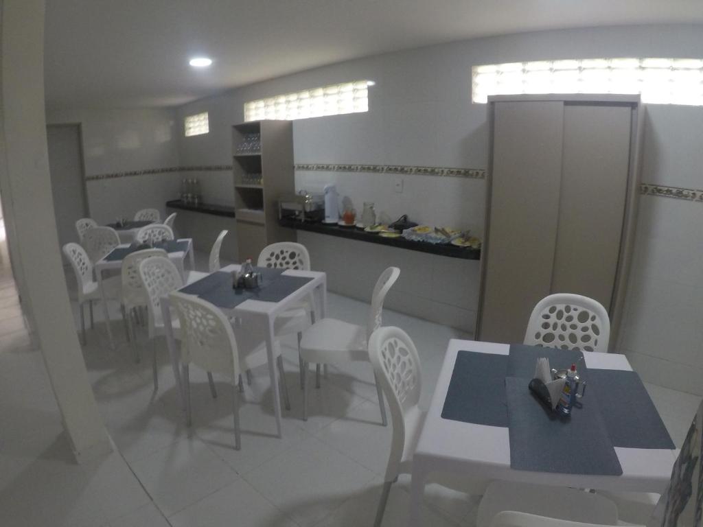 un comedor con mesas blancas y sillas blancas en Pousada Tambaú, en João Pessoa