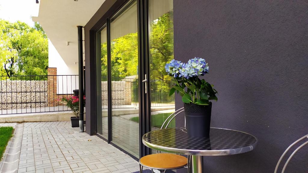 a table with a vase of blue flowers on it at Sirály apartman in Keszthely