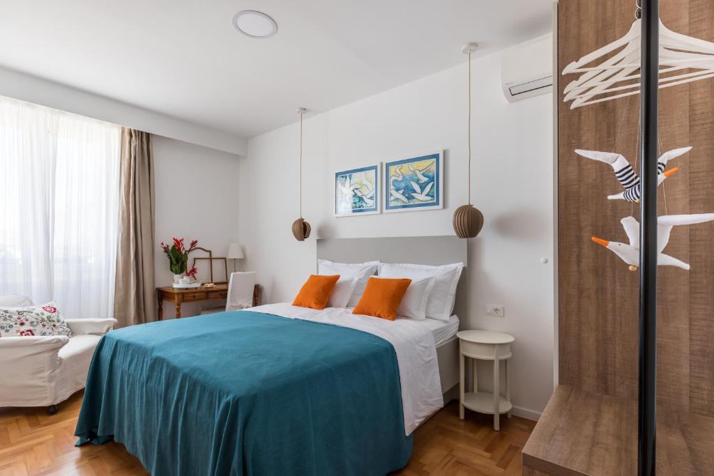 a bedroom with a bed with blue sheets and orange pillows at Promenade Room Split **** in Split