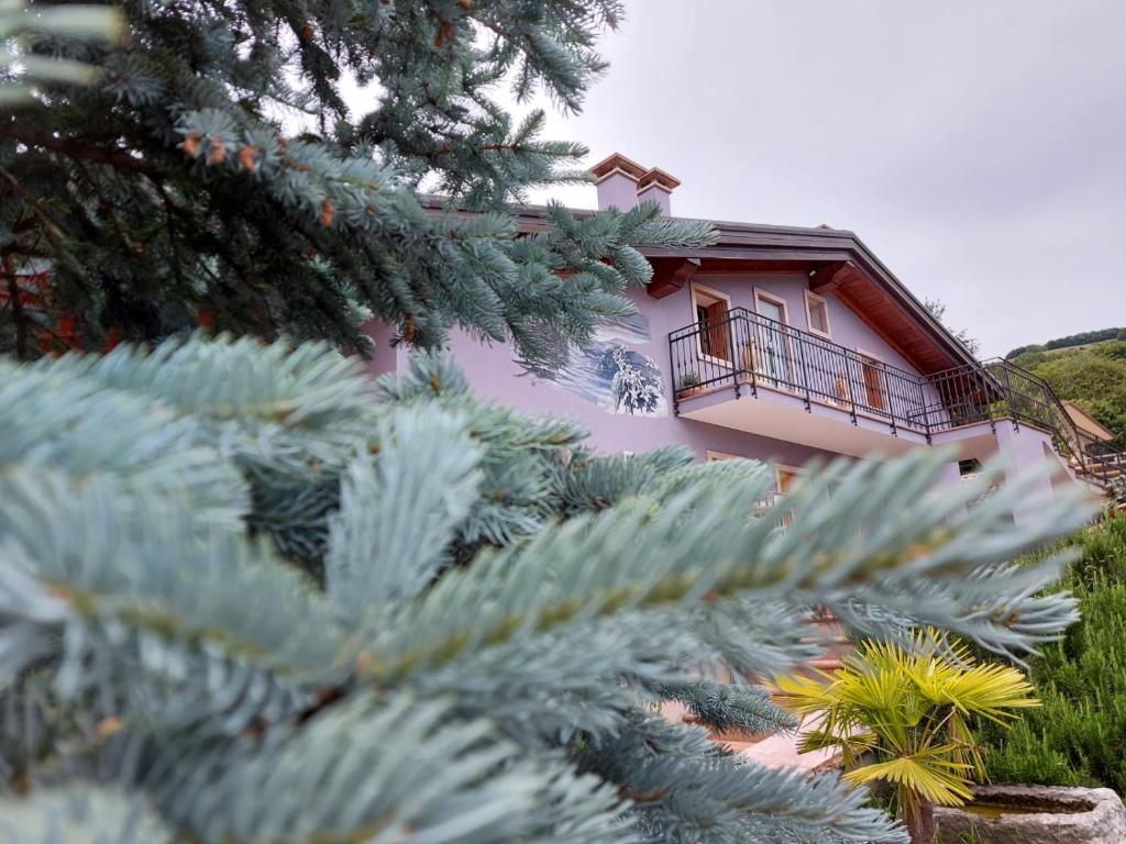 una casa rosa con balcone e alcune piante di B&B Stella Alpina a Fontanelle
