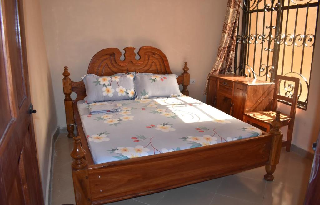 a bedroom with a wooden bed with flowers on it at Lunguya Lodge in Dar es Salaam