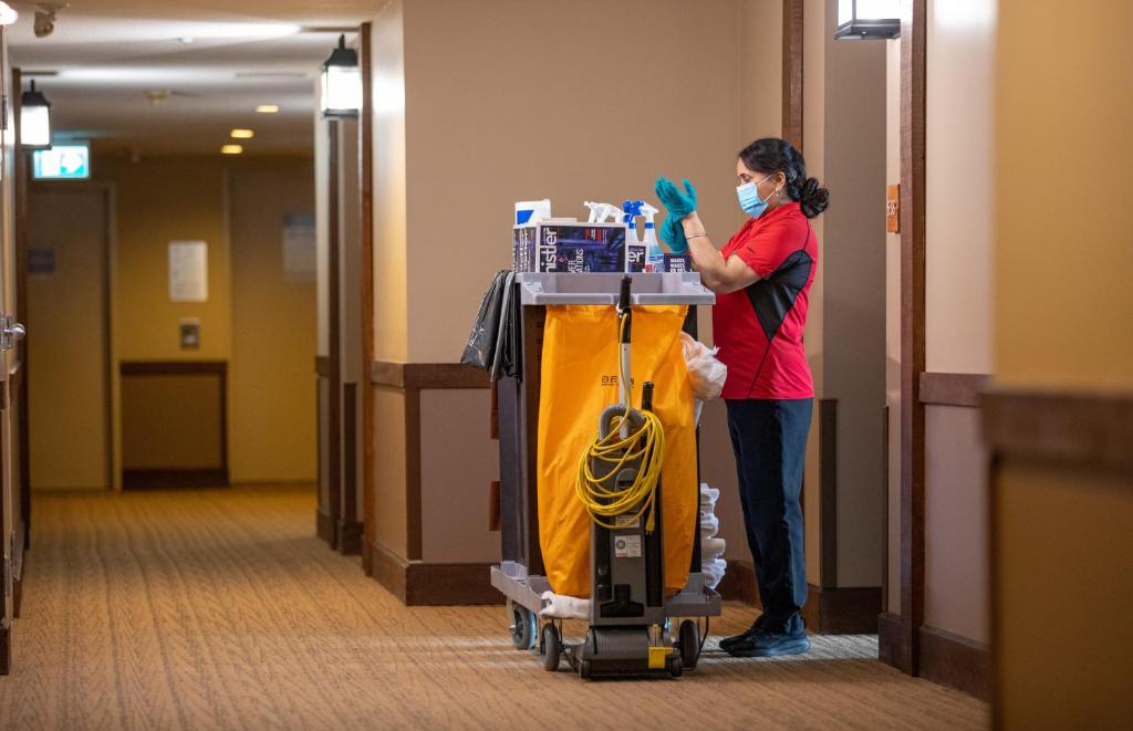 a woman wearing a mask and gloves standing next to a room at Blackcomb Springs Suites by CLIQUE in Whistler