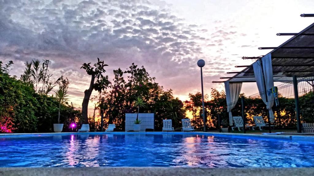 a large swimming pool with a sunset in the background at Casa Rural Mirador del Sol in Villalba del Alcor