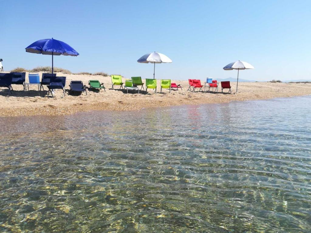 grupa leżaków i parasoli na plaży w obiekcie Villa Joanna 1 w mieście Mesimérion