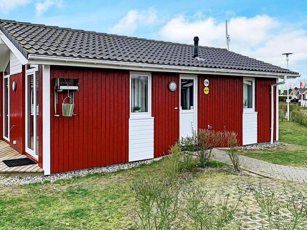 un cobertizo rojo con una puerta blanca y un patio en 4 person holiday home in GROEMITZ, en Grömitz