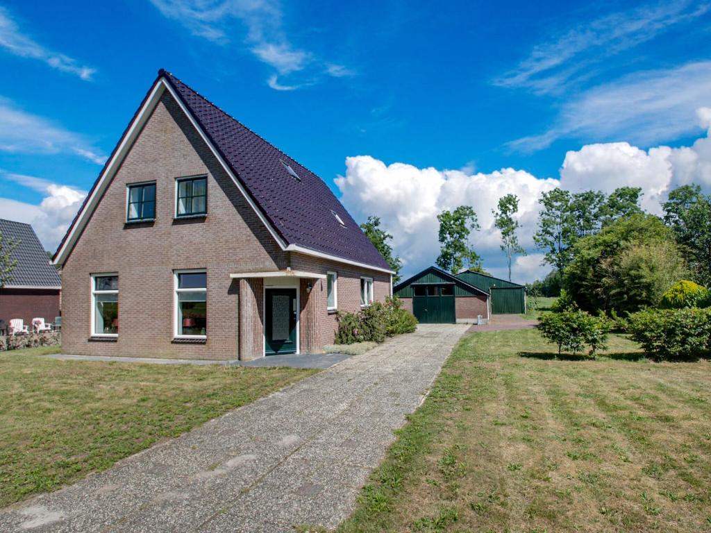 een groot bakstenen huis met een oprit in een tuin bij Classy Holiday Home in Langezwaag with Terrace in Langezwaag