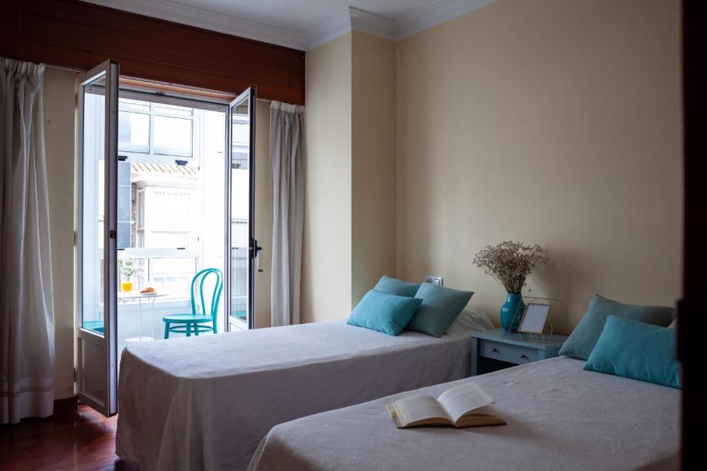 a bedroom with two beds with a book on them at TuristiQA - Piso C Arenal 20 2º VUT-CO-01678 in Ferrol