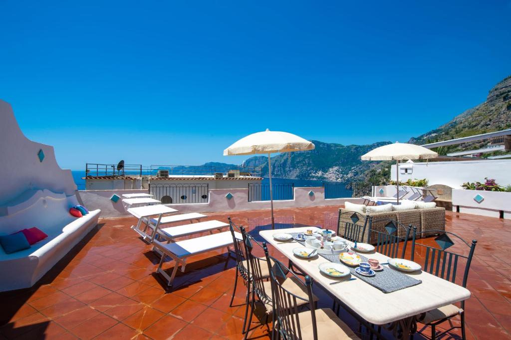d'une terrasse avec des tables et des chaises offrant une vue sur l'océan. dans l'établissement Casa Ella with Private Parking, à Praiano