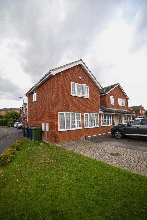 a red brick house with a car parked in the driveway at Fennec Apartments in Cherry Hinton