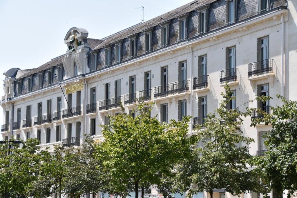 ein weißes Gebäude mit Bäumen davor in der Unterkunft Le Grand Hotel in Tours