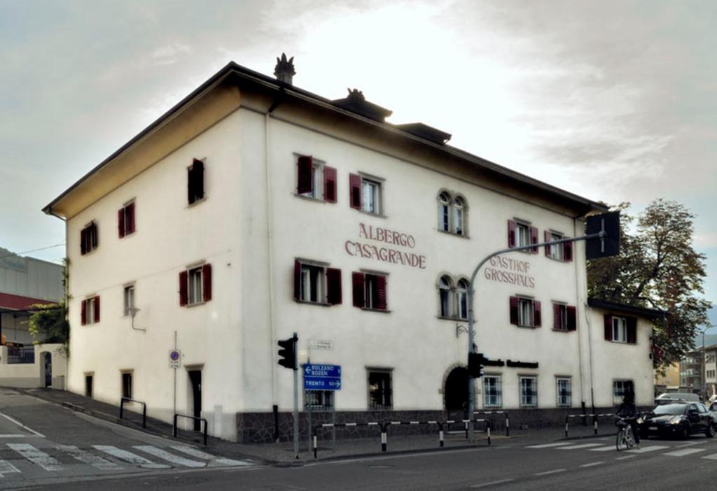 un grand bâtiment blanc au coin d'une rue dans l'établissement Albergo Casagrande, à Laives