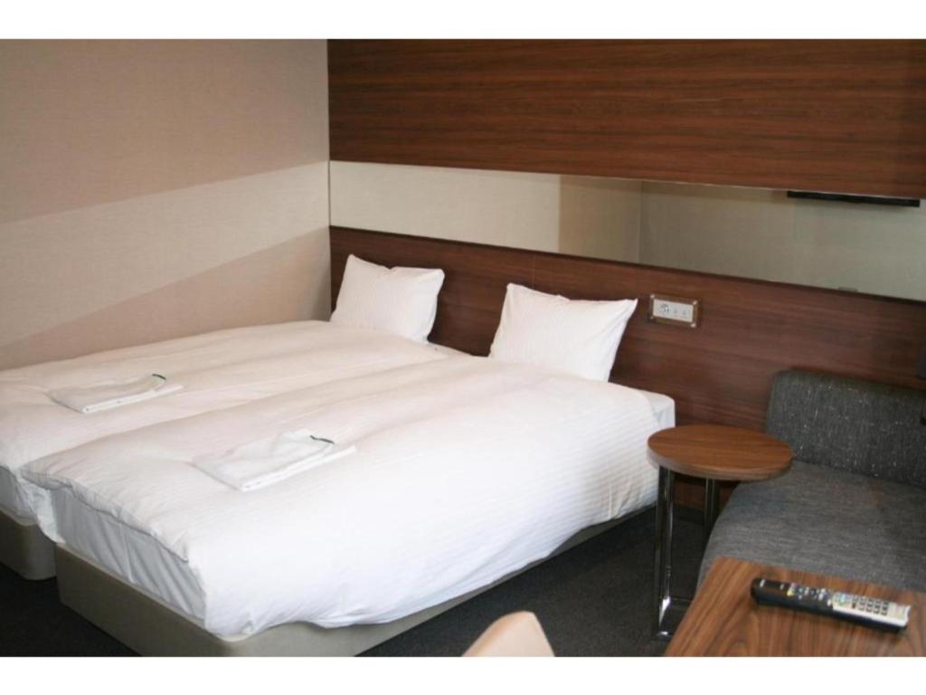 1 cama con sábanas blancas, mesa y silla en Hotel Il Credo Gifu - Vacation STAY 84636 en Gifu