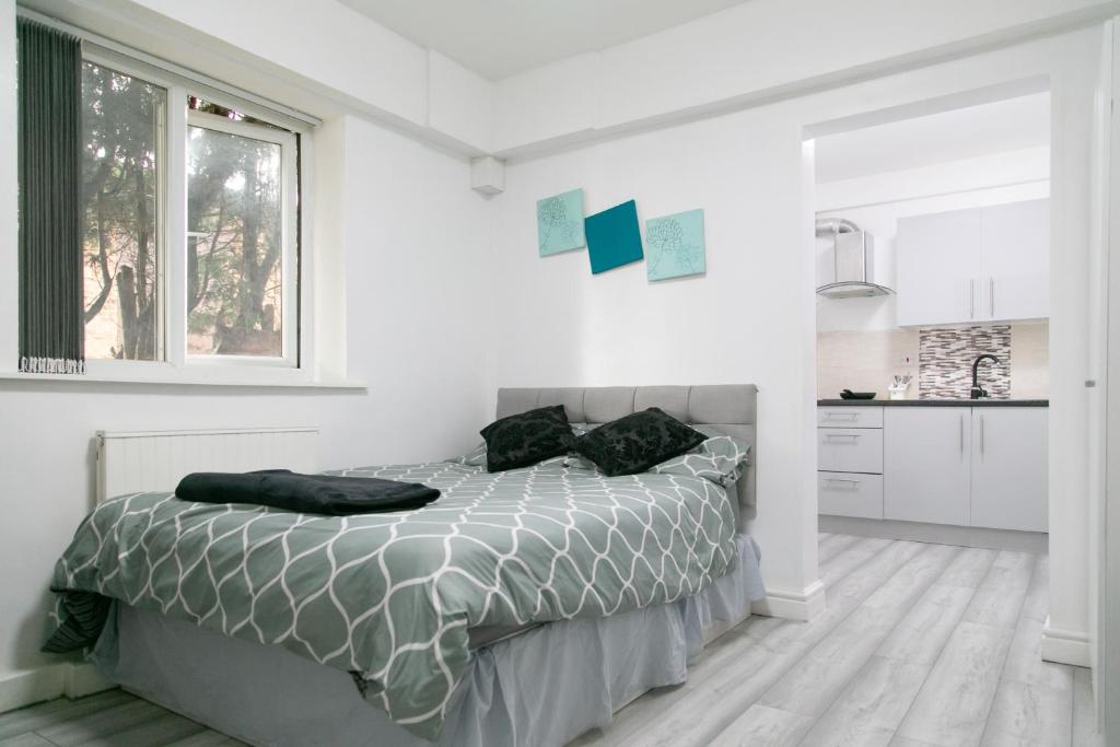 a white bedroom with a bed and a window at Cheetham Hills Apartments in Manchester