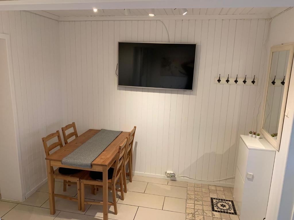 une salle à manger avec une table et une télévision murale dans l'établissement Nice and quiet apartment Kristiansand, à Kristiansand