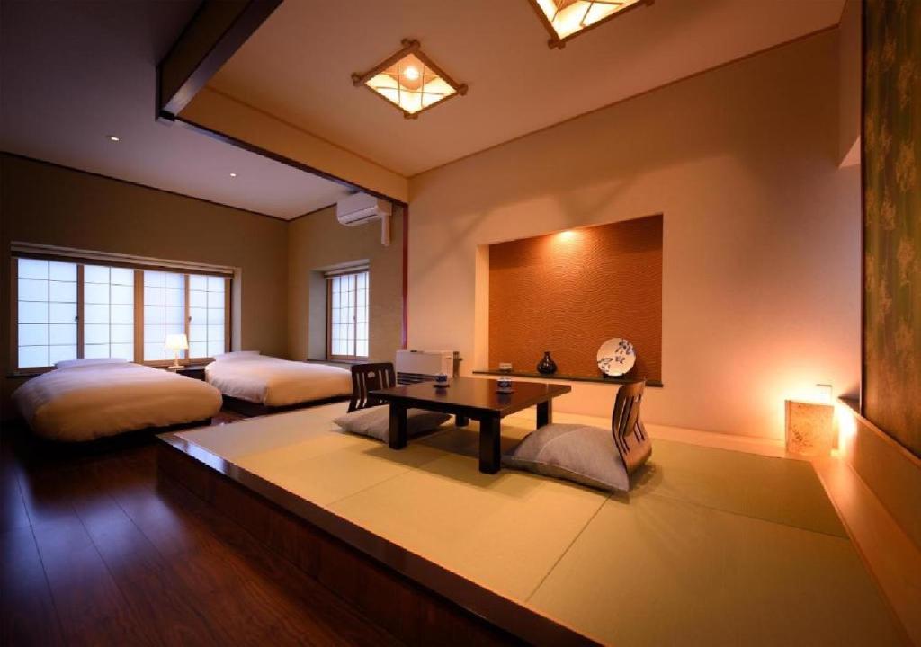 Dai Onsen Matsudaya Ryokan - Vacation STAY 67499 في هاناماكي: غرفة بسريرين وطاولة فيها