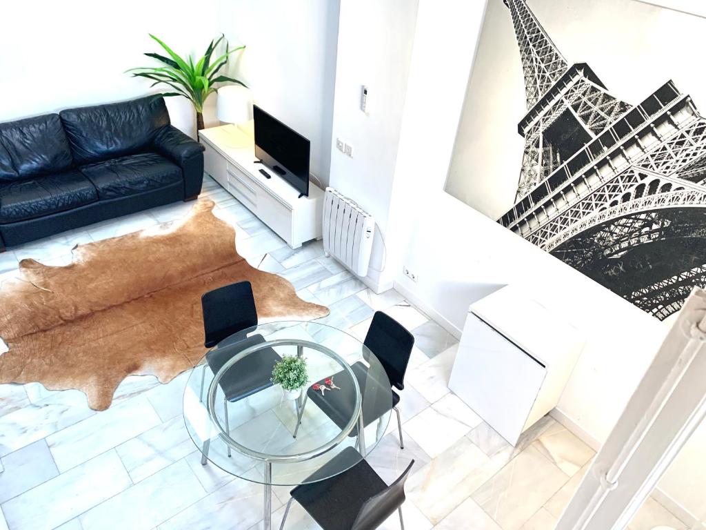 uma sala de estar com uma mesa de vidro e a torre Eiffel em Apartamentos Puerta del Sol-Rastro em Madri