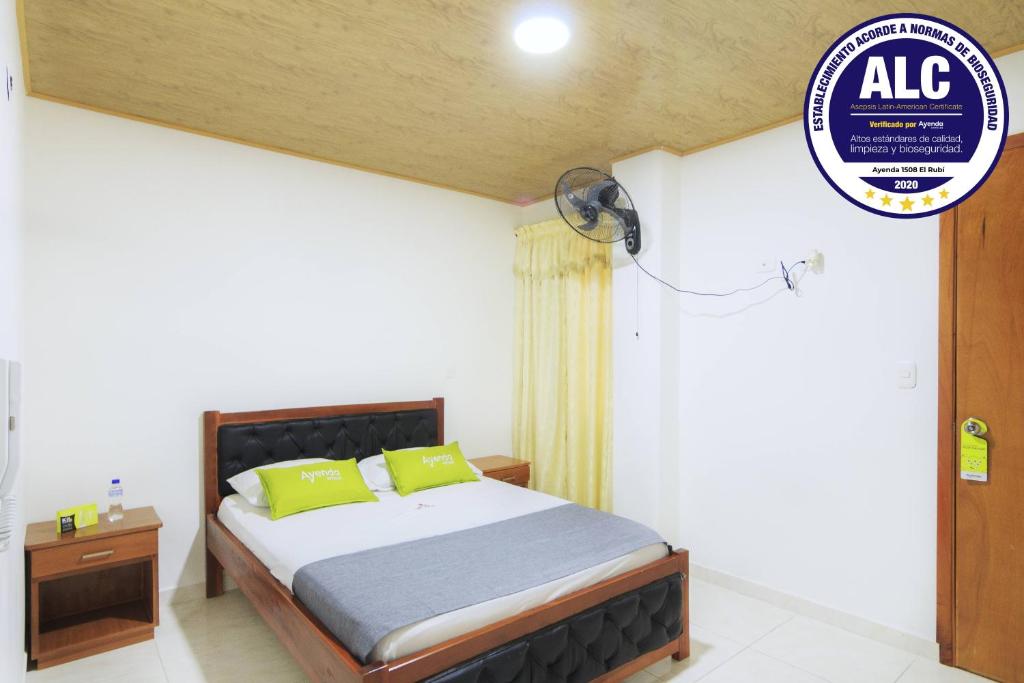 1 dormitorio con 1 cama con almohadas verdes en Hotel El Rubí, en Bucaramanga