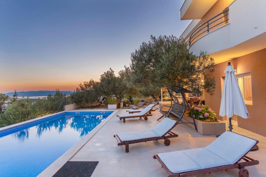 a swimming pool with two lounge chairs and a umbrella at House Arija in Makarska