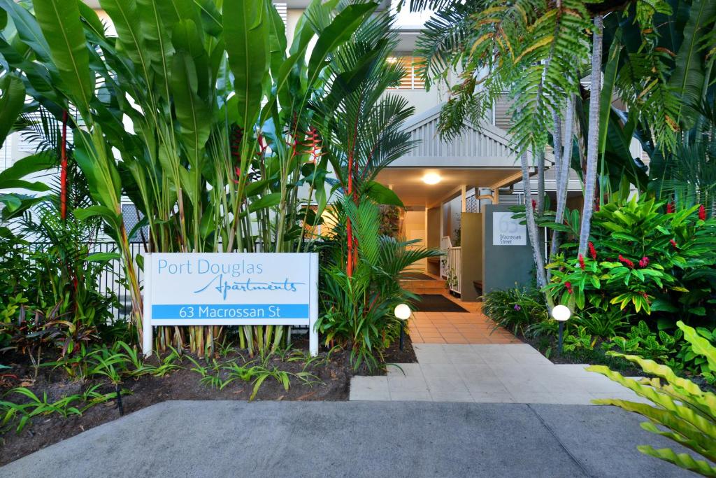 a sign in front of a building with plants at Port Douglas Apartments in Port Douglas
