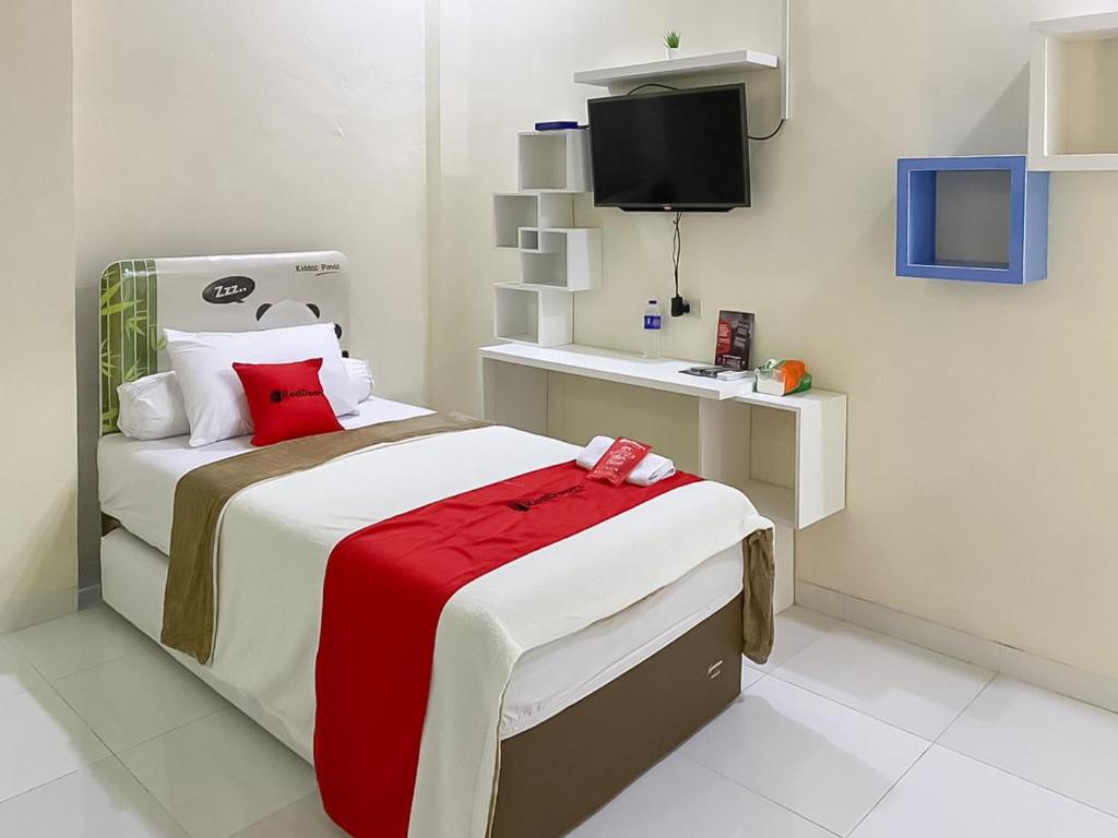 a bedroom with a bed with a red blanket at RedDoorz Syariah near PKOR Lampung in Bandar Lampung