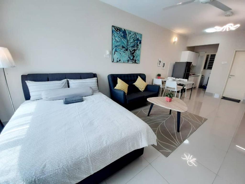 a bedroom with a large bed and a living room at Homey Galleria Suite A 10 12 in Seri Kembangan