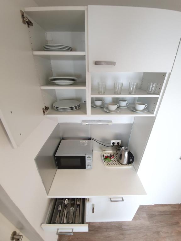 a kitchen with white cabinets with plates and dishes at Hotel Energie in Prague