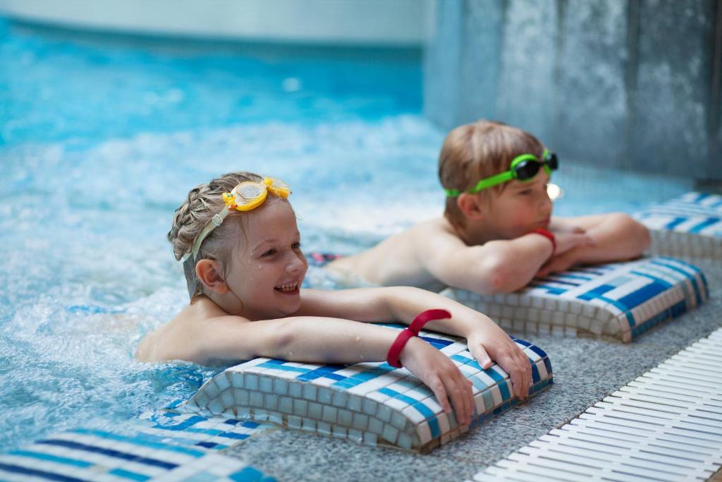 two young children swimming in a pool with goggles on their backs at Tallink Express Hotel in Tallinn