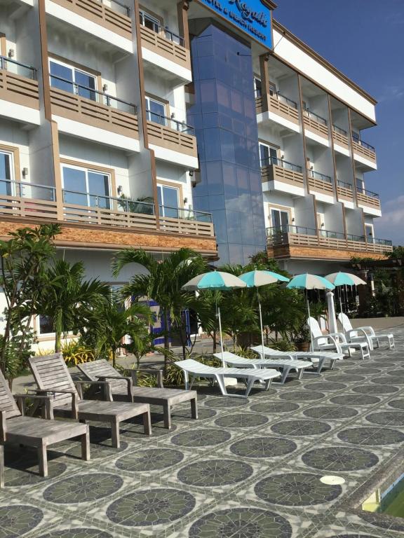 una fila de sillas y sombrillas frente a un edificio en EM Royalle Hotel & Beach Resort, en San Juan