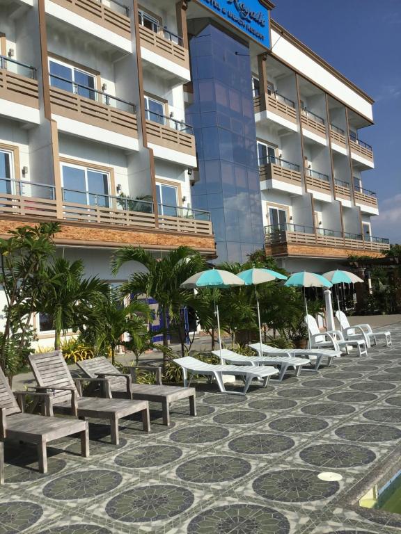 une rangée de chaises et de parasols devant un bâtiment dans l'établissement EM Royalle Hotel & Beach Resort, à San Juan