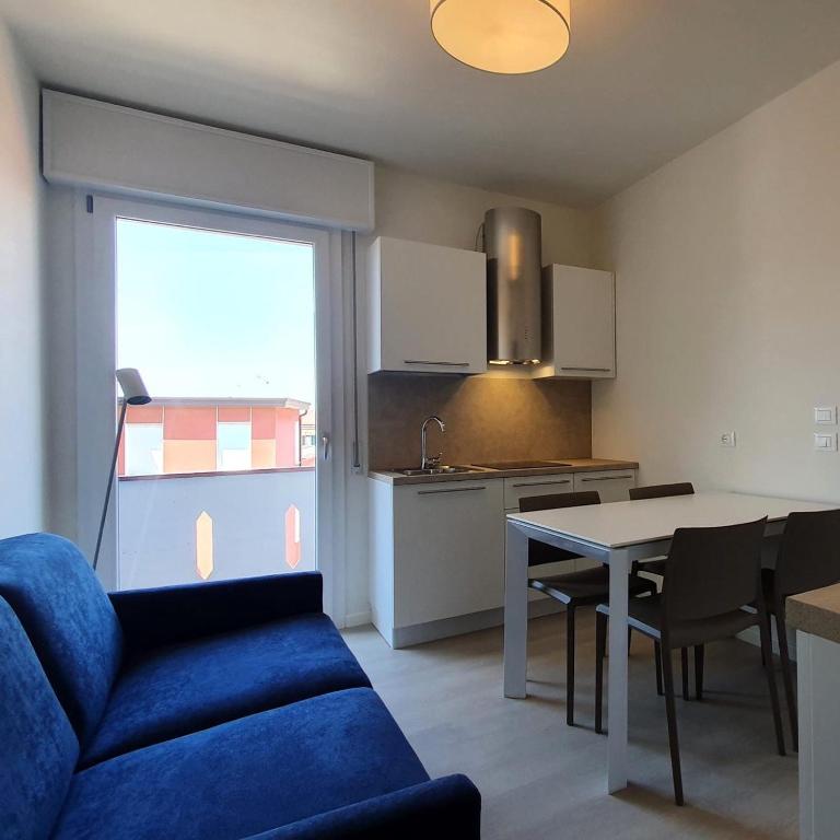 a living room with a blue couch and a kitchen at MAR60 Apartments in Caorle