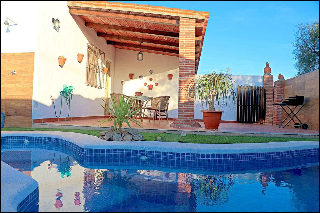 une maison avec une piscine en face d'une maison dans l'établissement Chalet acogedor con piscina, à Conil de la Frontera