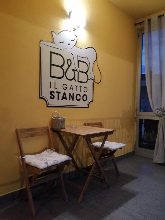 a sign for a restaurant with a table and two chairs at Il Gatto Stanco B&B in Arona