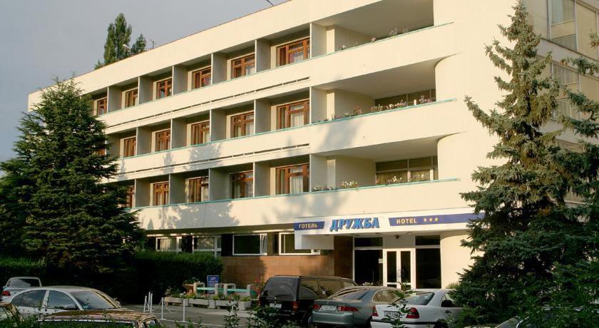 un gran edificio blanco con coches estacionados frente a él en Druzhba Hotel, en Uzhhorod