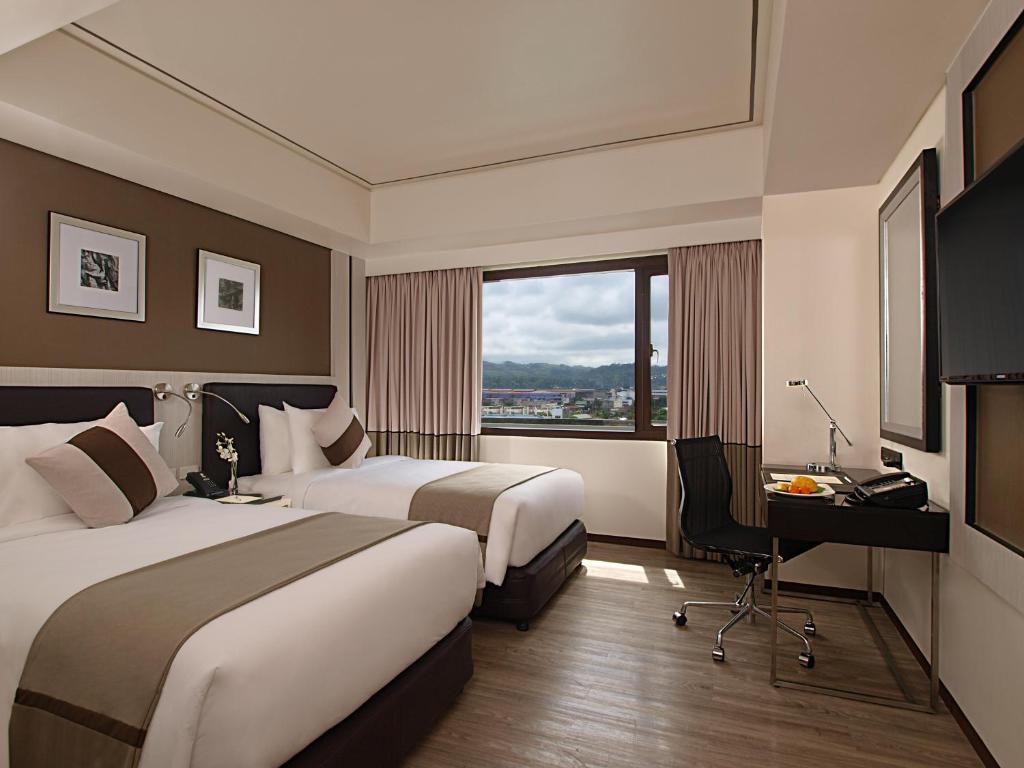 um quarto de hotel com duas camas e uma secretária e uma janela em Seda Centrio em Cagayan de Oro