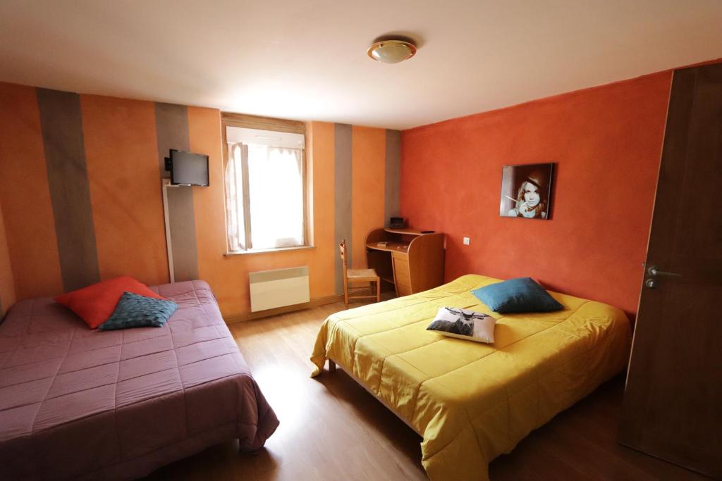 2 camas en una habitación con paredes de color naranja en Le Ptit Ecureuil en Tosse