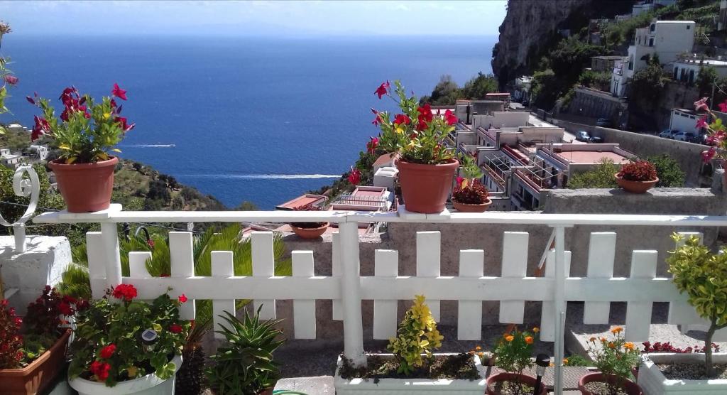 una cerca blanca con flores y el océano en el fondo en CASA ENZO con vista mare en Amalfi