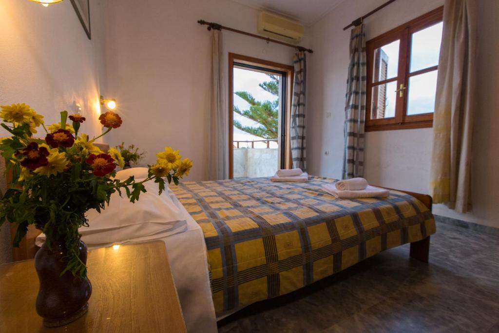 1 dormitorio con 1 cama y un jarrón de flores sobre una mesa en Filoxenia Apartments 2 en Palaiochóra