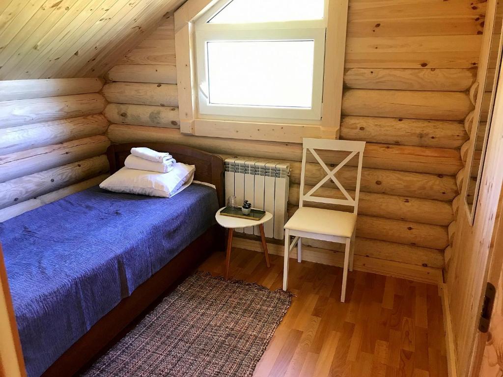 a bedroom with a bed and a chair in a log cabin at Kurna Saunaküla in Kurna