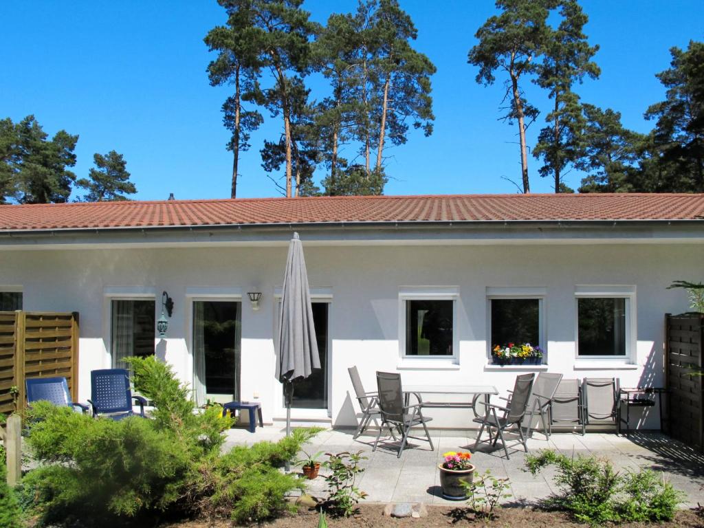 a white house with chairs and an umbrella at Holiday Home Am Walde by Interhome in Lubmin