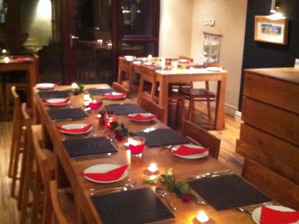 a long wooden table with red and white dishes on it at Blas Gwyr in Llangennith