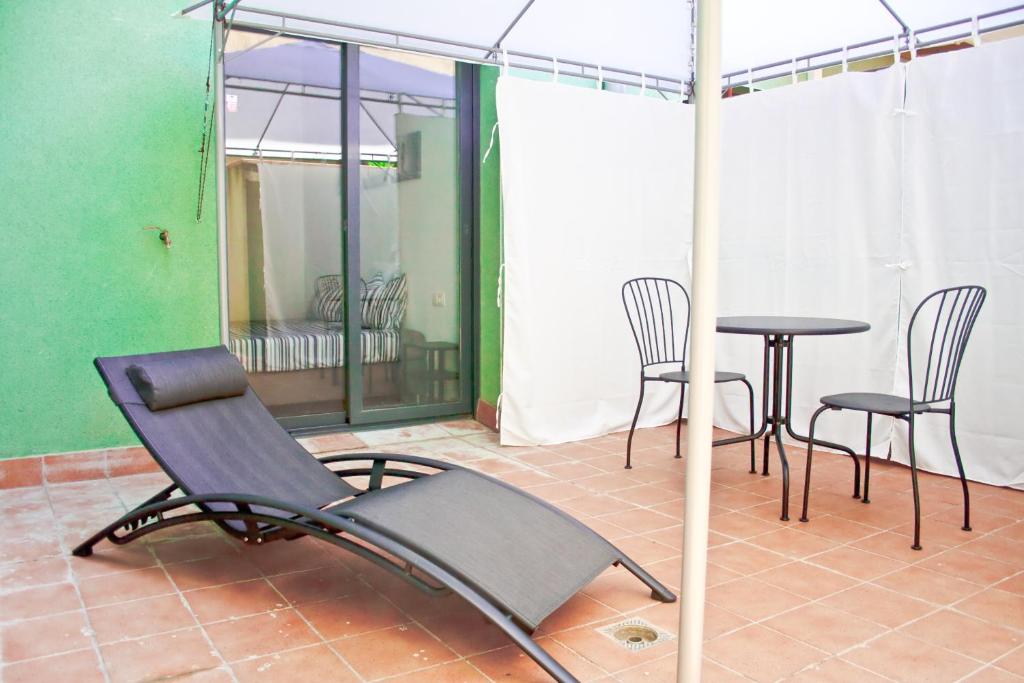 曼雷沙的住宿－Urban Manesa city center apartment with private patio，一把椅子和一张桌子,放在带雨伞的房间