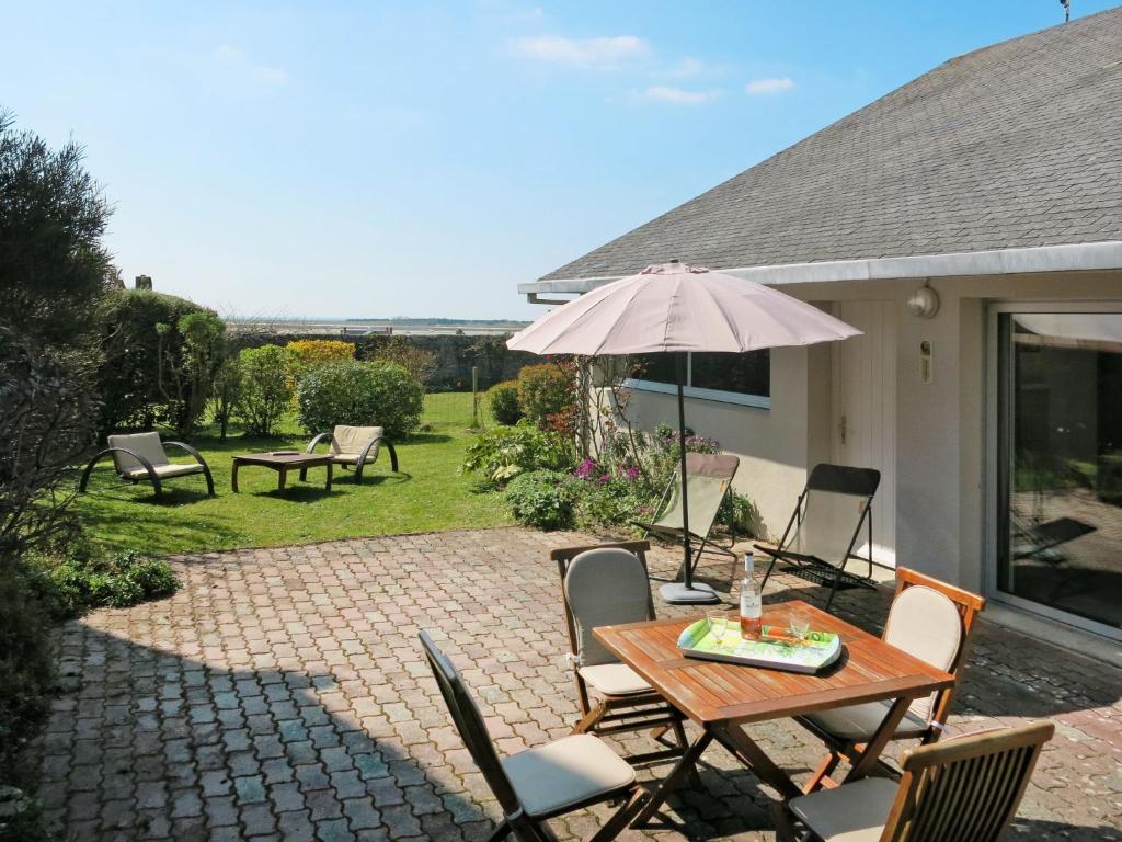 un patio avec une table, des chaises et un parasol dans l'établissement Holiday Home Le Petit Clos by Interhome, à Regnéville-sur-Mer