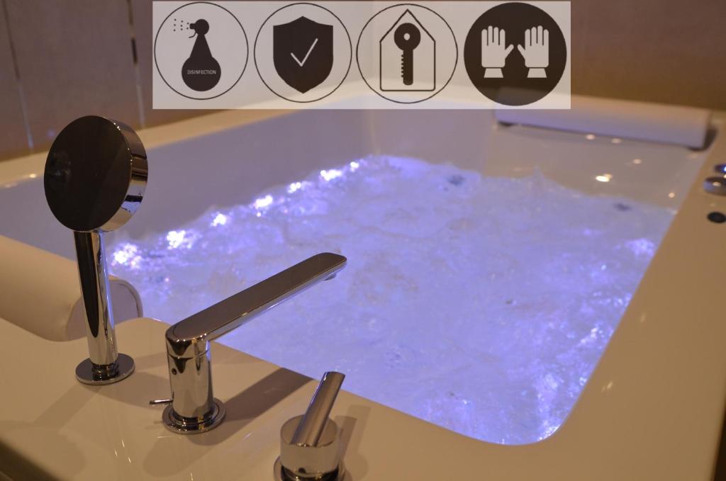 een badkamer met een bad gevuld met blauw water bij Jacuzzi Apartments in Krakau