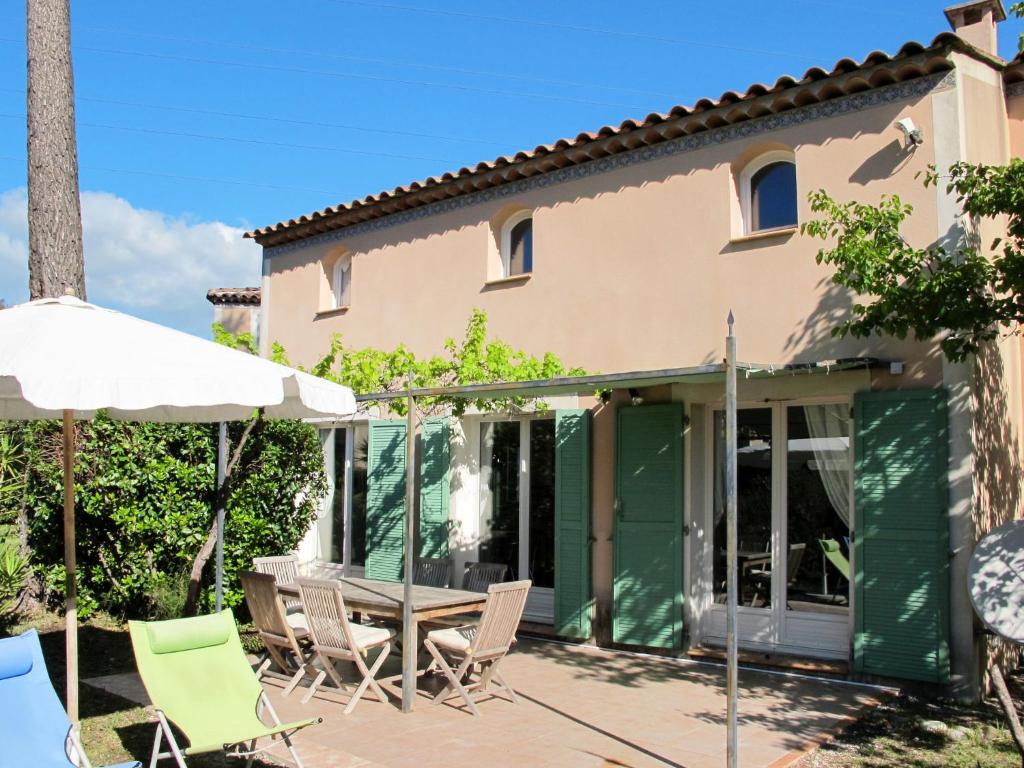 - une terrasse avec des chaises et un parasol à côté d'une maison dans l'établissement Holiday Home Olivier by Interhome, à Mougins