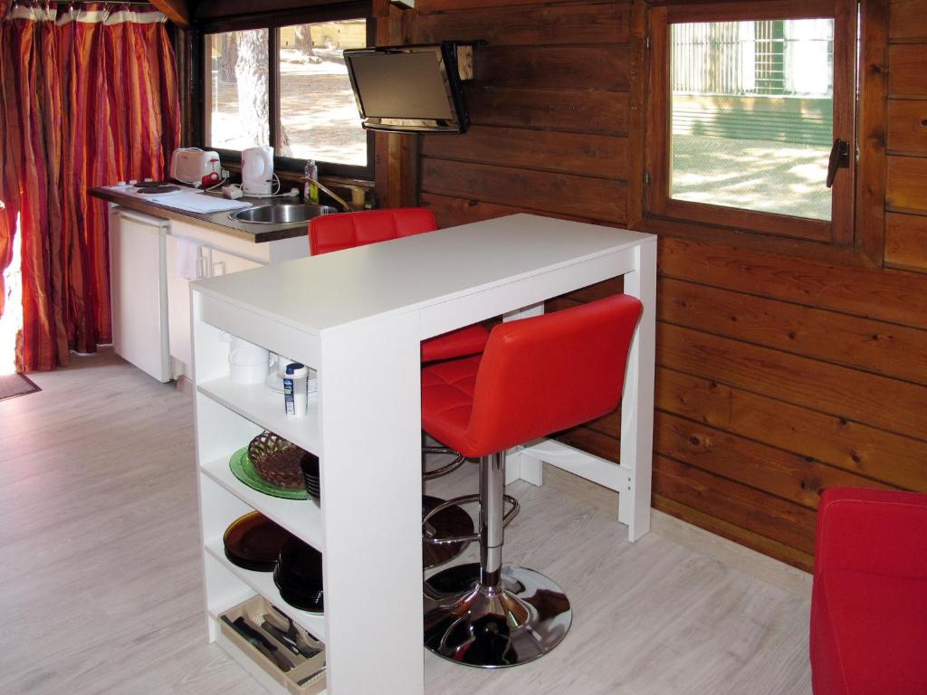 a kitchen with a white counter and red chairs at Holiday Home Chalet 2 pers by Interhome in Calvi