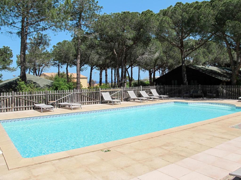 a swimming pool with lounge chairs and a fence at Holiday Home Tramariccia-3 by Interhome in Calvi